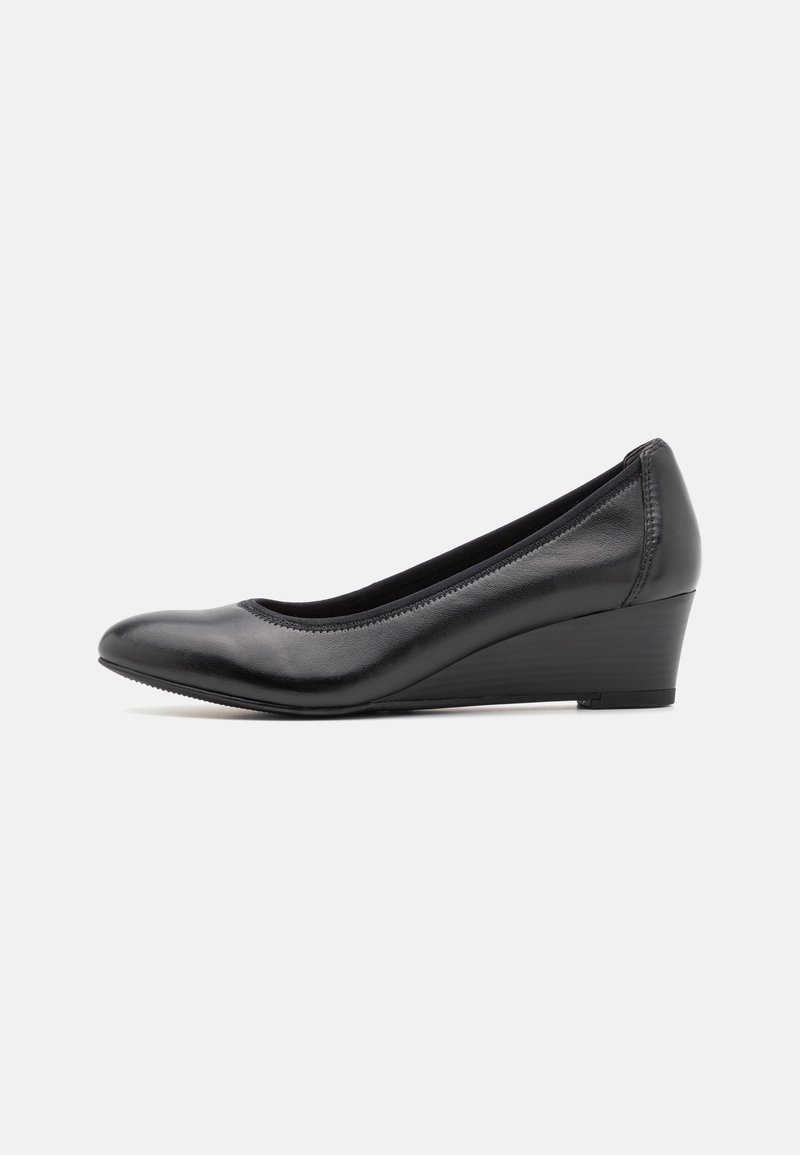 Chaussure à semelle compensée en cuir noir avec un bout arrondi et un talon bas, vue de profil sur un fond gris clair.