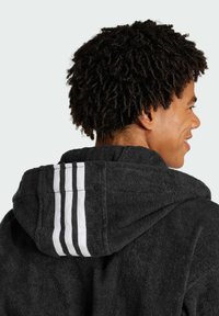 Black terry cloth hooded robe with white three-stripe design on the back. Features a soft texture and a relaxed fit.