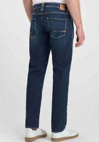 Vaqueros de mezclilla azul oscuro con corte recto, que cuentan con dos bolsillos traseros, detalles de costura sutiles y un parche de cuero marrón en la cintura.