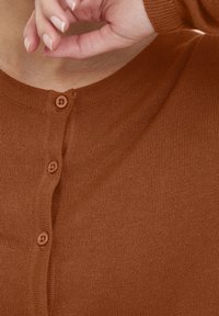 Brun ribbad cardigan med rund halsringning och fem matchande knappar fram, med en slät struktur och en tight passform.