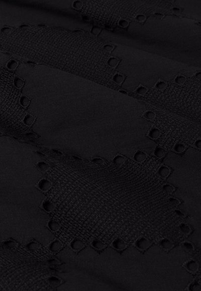 Tessuto nero con intricati motivi ritagliati e sezioni texturizzate, con aree lisce e intrecciate alternate per profondità e dettaglio.
