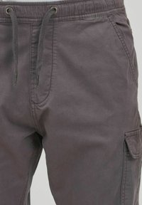 Grijze cargobroek met een trekkoord in de taille, zijzakken en een gladde, duurzame stof met een matte afwerking.
