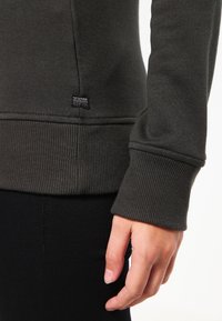 Felpa grigia scura con polsini e orlo a coste, tessuto morbido e un piccolo etichetta del marchio vicino alla cucitura inferiore.