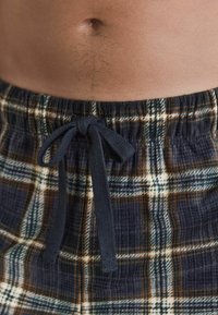 Karierte Lounge-Shorts in Marineblau, Beige und Weiß, mit einem elastischen Bund und einem Kordelzug. Baumwollmaterial mit einer strukturierten Oberfläche.