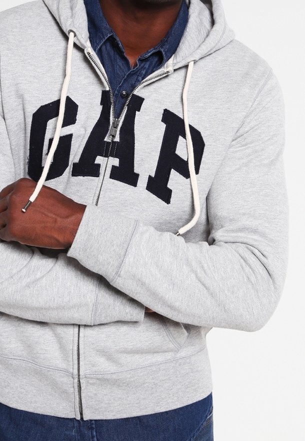 Felpa grigia con zip e grande logo nero "GAP" sul petto, dotata di cappuccio e lacci, realizzata in morbido cotone.