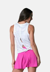 Top bianco senza maniche con sottili righe orizzontali, caratterizzato da un design con nodo sul retro e un dettaglio con taglio, abbinato a pantaloni corti rosa plissettati.