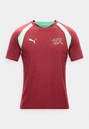 Bordowa sportowa koszulka z jasnzielonymi paskami na ramionach, subtelnym wzorem, logo Puma na prawej piersi oraz emblematem Szwajcarskiej Federacji Hokeja na Trawie na lewej piersi.