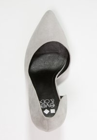 Décolleté grigio in suede con tacco alto, punta affusolata e lati intagliati. L'interno presenta una soletta nera con logo e una texture liscia.