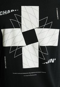 Juodas marškinėliai su geometriniu baltu dizainu, kuriame susipina linijos ir teksto akcentai. Tekstas skaito "C-COMMUNITY" ir "TYRIMŲ LABORATORIJA."