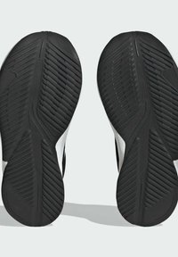 Soli di scarpe sportive in bianco e nero, con un motivo in gomma testurizzata e un design curvo per trazione e stabilità.