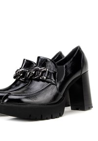 Černé lakované platformové boty s masivním podpatkem, zdobené řetízkem v přední části a texturovanou podešví pro lepší přilnavost.