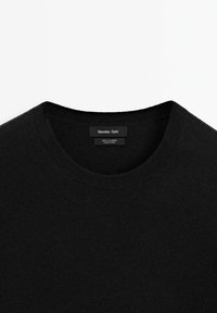 Maglione in cashmere nero con scollo rotondo. Presenta una trama liscia e un design minimalista. Etichetta del brand visibile sul collo.