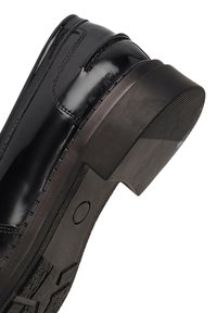 Zwarte leren schoen met een glanzende afwerking, een lage hak, een gestructureerde zool en zichtbare stiksels langs de bovenrand.