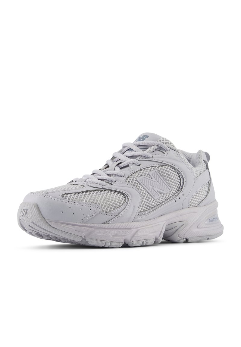 Scarpa atletica grigia chiaro con tomaia in rete e materiale sintetico, suola spessa, design con lacci e accenti di logo discreti. Punta arrotondata e colletto imbottito.