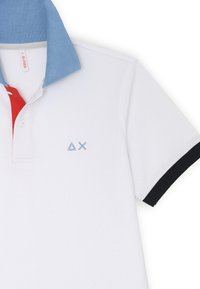 Polo in tessuto bianco con colletto blu, patta rossa, dettagli neri sulle maniche e un logo azzurro chiaro sul petto. Fit classico.
