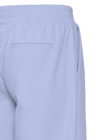 Pantalons de survêtement bleu clair avec un waistband élastique, comprenant une seule poche arrière et une texture de tissu douce et lisse.