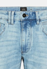 Slim-fit jasnoniebieskie dżinsy z efektem zniszczenia, z zapięciem na guzik i szlufkami na pasek. Widoczna metka marki na pasku.