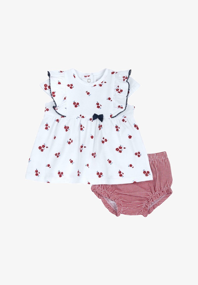 Hvid blomsterkjole med røde blomster og blå accenter, der har flæseærmer og en marineblå sløjfe. Kombineret med røde gingham shorts.