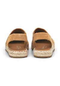 Sandales en suede beige avec dos ouvert, bout rond et semelle en jute tissé. Caractéristiques : bande ajustable et doublure intérieure douce.
