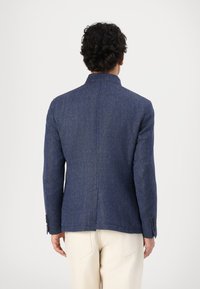 Sötétkék blazer texturált anyagból, hajtott gallérral és gombos mandzsettával. Hátsó szellőzővel és testhezálló szabással rendelkezik.