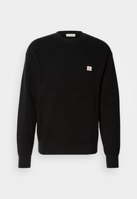 Zwarte gebreide trui met ribbeltextuur, ronde hals, en een klein wit en rood logo-opdruk op de linkerkant van de borst. Classieke pasvorm met lange mouwen.