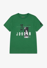 Zielona bawełniana koszulka z czarno-białymi grafikami, w tym numerem "23" i nazwą "JORDAN", z logo Nike na rękawie.