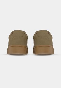 Ζευγάρι καφέ σουέντ αθλητικά παπούτσια, εμφανιζόμενα από πίσω, με καφέ λαστιχένιες σόλες πάνω σε απλό λευκό φόντο.