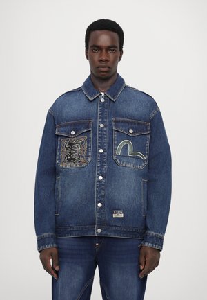 Giacca di jeans di colore blu scuro con tasche frontali, cuciture a contrasto e design ricamati sul lato sinistro del petto e sulla tasca destra.