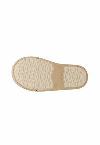 Semelle de sneaker en caoutchouc beige clair avec des vagues texturées, des motifs circulaires et un marquage en relief ; matériau lisse et flexible avec des trous de drainage.