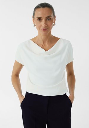 Witte top met cowl-neck en korte mouwen, gemaakt van een gladde stof met een elegante val, gecombineerd met donkere broeken. Minimalistisch ontwerp, strakke lijnen en zonder patronen.