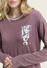 Maglietta a maniche lunghe color bordeaux con scollatura rotonda, caratterizzata da un design grafico bianco sul lato sinistro. Tessuto morbido e strutturato.