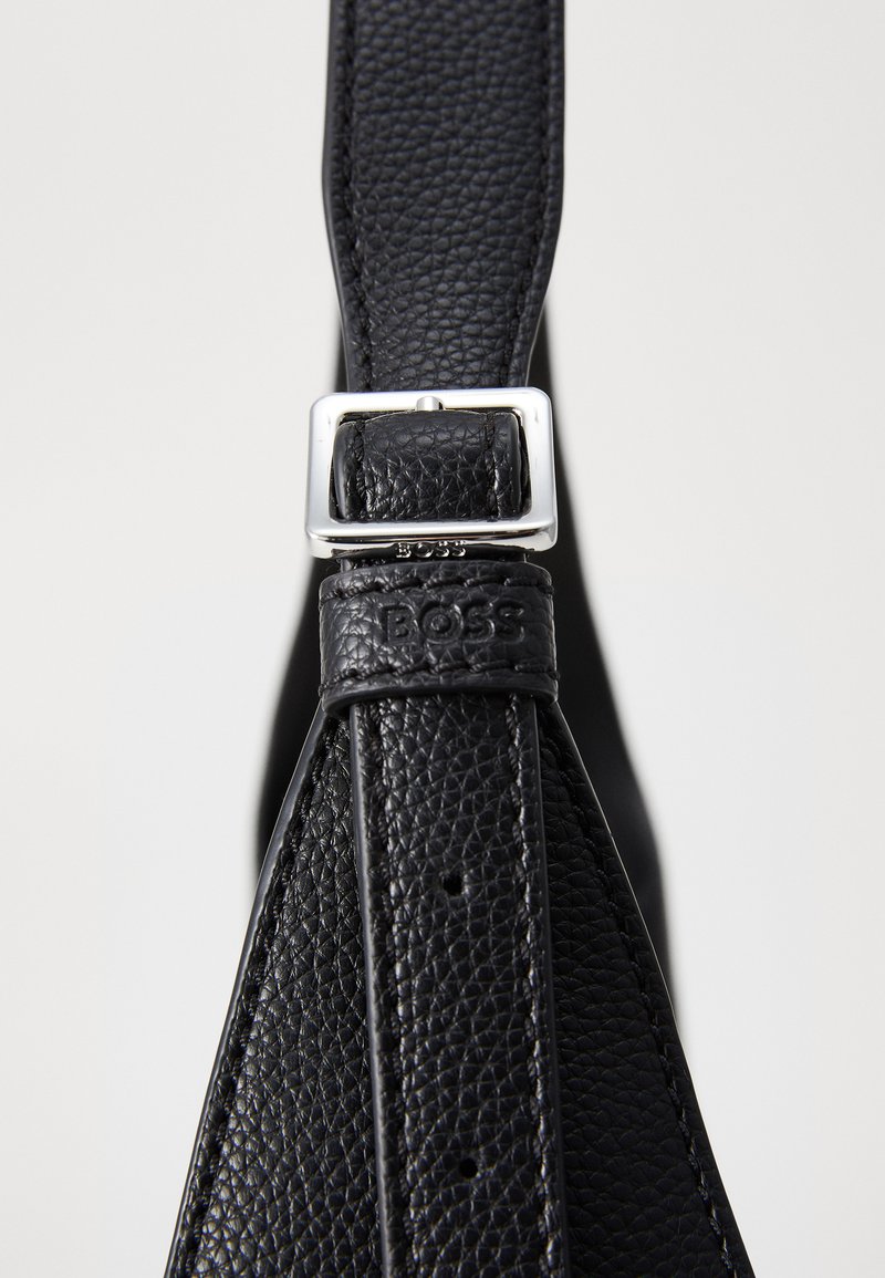 Cinturino in pelle nera testurizzata con fibbia in metallo argento. Presenta un logo impresso sul cinturino, mettendo in evidenza un design elegante e un dettaglio funzionale.