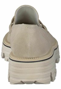 Bežist sueded slip-on king, millel on paks, tekstureeritud kummitald, millel on sooneline muster ja kontrastne must riba talda ääristamas.