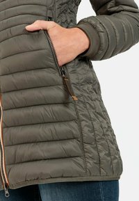 Pufferjack in olijfgroen, met een gequiltte structuur, zijzak met rits en ribgebreide cuffs. Ritsaccenten in contrasterende kleur.