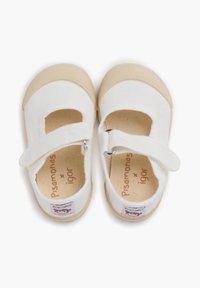Zapatos Mary Jane de lona blanca con suela de goma beige, correa ajustable y logo de la marca impreso en la plantilla.