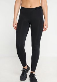 Černé sportovní legíny vyrobené z elastického materiálu s texturovaným vzorem a vysokým pasem, na kterém se nachází logo "NIKE PRO".