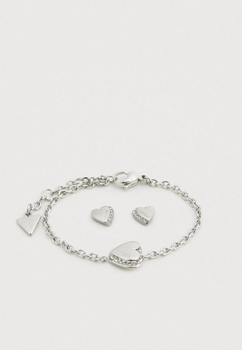 Bracelet ton argent avec un design en chaîne, orné de breloques en forme de cœur avec un texte gravé et une breloque décorée de strass.