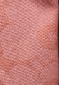 Roze stof met subtiel geweven patroon en grote abstracte bloemen in iets donkerder roze tinten.