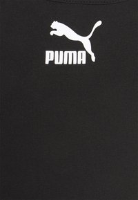 Top deportivo negro con textura acanalada y un logotipo PUMA blanco que incluye un diseño de gato saltando. Ropa deportiva sencilla y funcional.