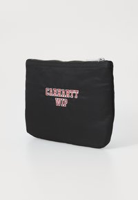 Pochette en nylon noir avec une fermeture éclaire argentée et un logo "Carhartt WIP" brodé en rouge sur le devant. Forme rectangulaire avec une texture lisse.