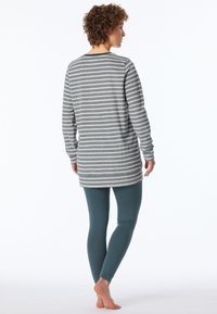 Grå och vitrandig långärmad topp kombinerad med teal leggings. Toppen har en avslappnad passform, rundad nederkant och bekväm tyg.