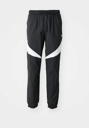 Pantalones deportivos negros con cintura elástica y cordón ajustable. Presenta paneles curvados blancos a los lados y puños elásticos en los tobillos.