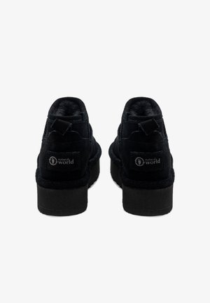 Botines de ante negros con un acabado texturizado, puntera redondeada y un tacón pequeño. Presenta un parche de logo en la parte trasera y una lengüeta.