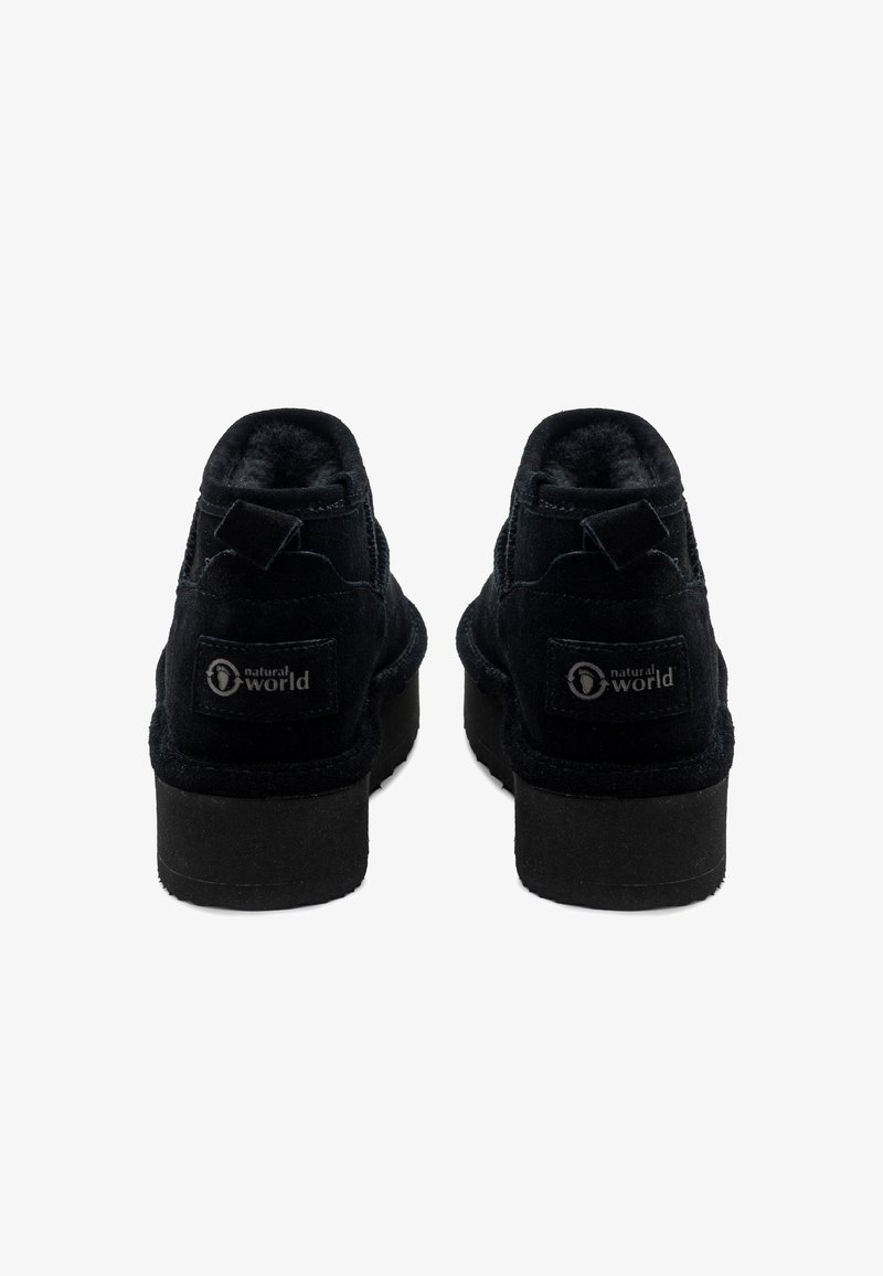 Botines de ante negros con un acabado texturizado, puntera redondeada y un tacón pequeño. Presenta un parche de logo en la parte trasera y una lengüeta.