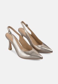 Tacones slingback de metal plateado con puntera puntiaguda, un tacón de aguja de 7 cm y una correa ajustable con detalle de herraje redondo.