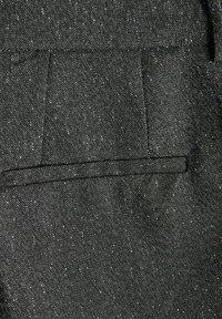 Tissu noir avec un motif discret en points, mettant en valeur une poche arrière sobre et bien taillée. La texture semble lisse et résistante.