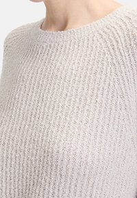 Light beige knit sweater with a ribbed texture and round neckline. The fabric appears soft and slightly elastic, featuring vertical lines.