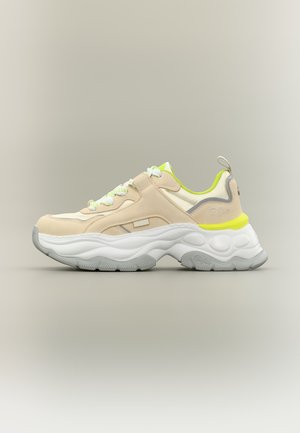 Beige-weißer klobiger Sneaker mit neon-gelben Akzenten, strukturierter Sohle, Schnürung vorne und Schlaufe auf neutralem Hintergrund.