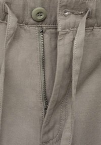 Pantalones grises con cierre de botón, cremallera y cordón. La tela es suave con detalles de costura visibles.