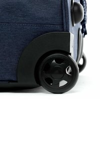 Marinefarbener Koffer aus Stoff mit einem schwarzen, strukturierten Kunststoffboden und großen, runden Rädern mit Ausschnitten für bessere Mobilität.